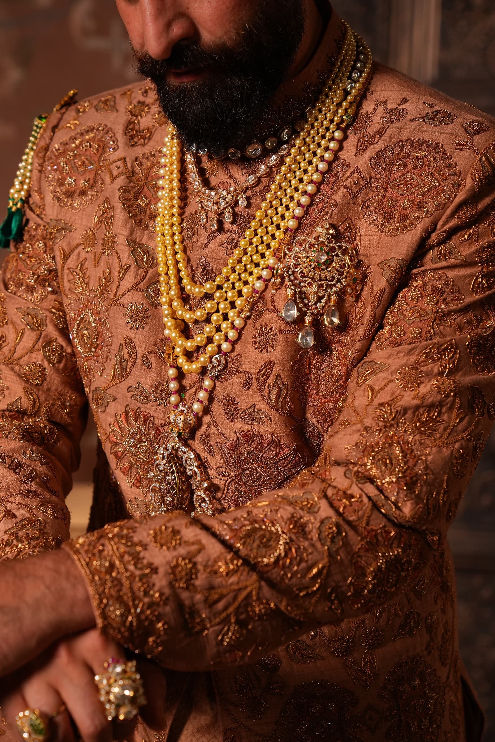 Zardozi embroidery worked by hand across the chest of a copper silk sherwani, layered with strands of gold and pearl